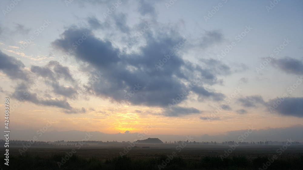 Natural Sunset Sunrise Over Field Or Meadow. Bright Dramatic Sky And Dark Ground. Countryside Sun Over Skyline, Horizon. Cold Colours Natural Sunset Sunrise Over Field Or Meadow. Bright Dramatic Sky And Dark Ground. Countryside Sun Over Skyline, Horizon. Cold Colours