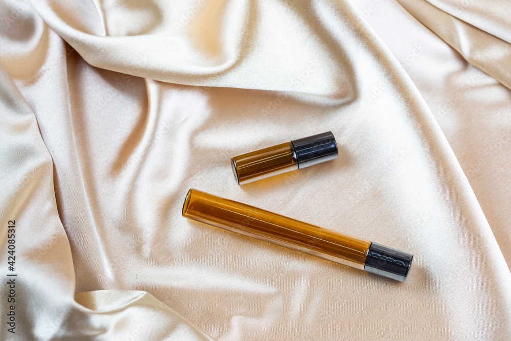 Naklejka premium A container for storing cosmetics made of dark glass lie on the folds of a silk