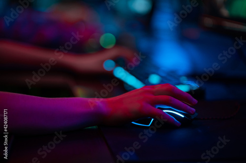 Close-up of the gamers hand movements on the glowing keyboard and mouse