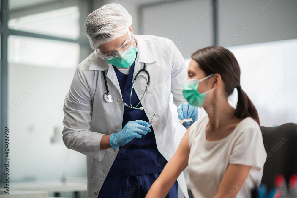 In a medical laboratory, a young woman is vaccinated against coronavirus during a pandemic In a medical laboratory, a young woman is vaccinated against coronavirus during a pandemic