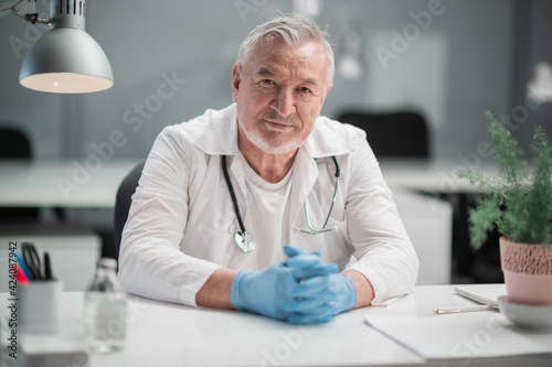 A professor of medical sciences conducts an internship in a hospital, he sits at a table and looks at the camera