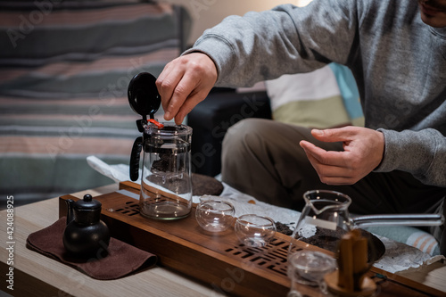 The process of tea ceremony at home. The tea master puts pieces of raw aged black tea in a teapot on a bamboo tray.