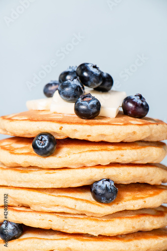 Tall stack of homemade buttermilk pancakes with fresh blueberries on a white wooden board