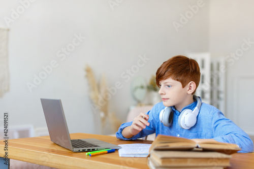 Teen boy doing homework online at home. He closely follows the teacher's story online.