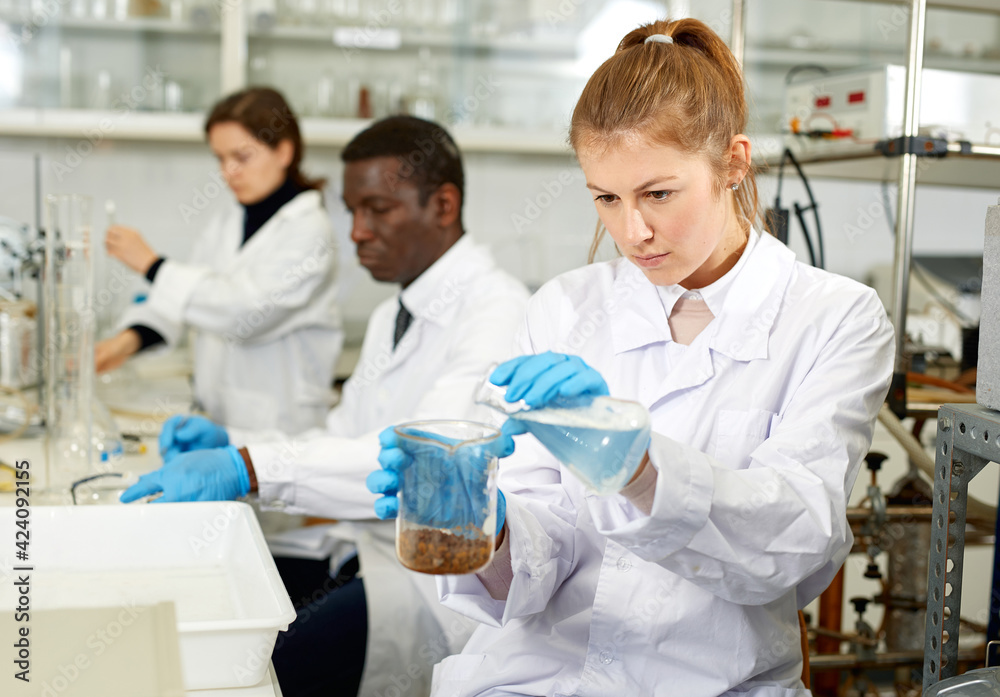 Fototapeta premium Serious woman lab scientist in glasses working with reagents and test tubes in laboratory