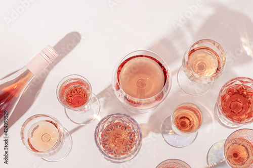 Many glasses of rose wine and bottle sparkling pink wine top view. Light alcohol drink for party.