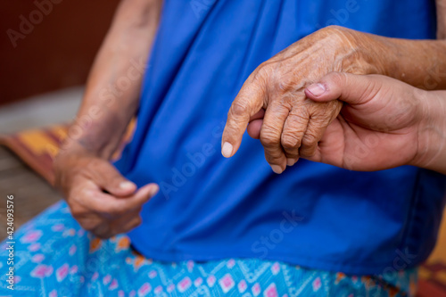 Close-up of the Old lady hands A man holding a grandmother's hand looks warm caring for the elderly in the family Old lady with a traditional Thai dress
