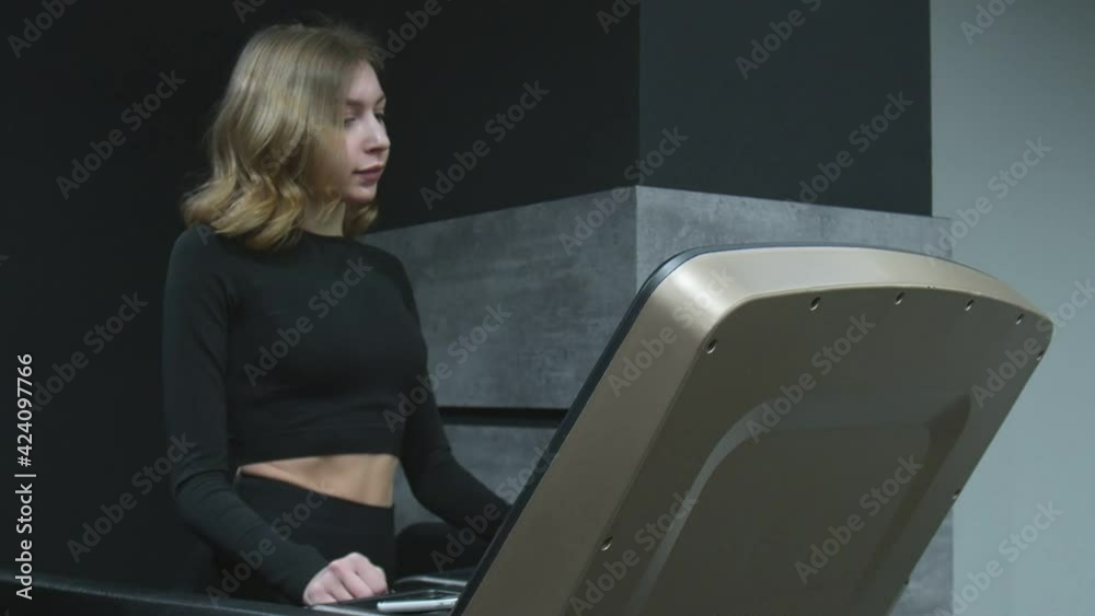 Fitness woman walks warm up on treadmill in gym. Athlete woman using run machine in fitness center Fitness woman walks warm up on treadmill in gym. Athlete woman using run machine in fitness center