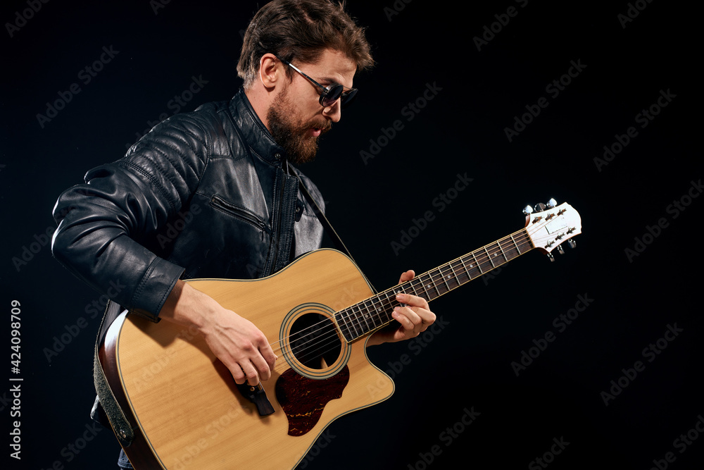 Naklejka premium A man with a guitar in his hands leather jacket music performance rock star modern style dark background