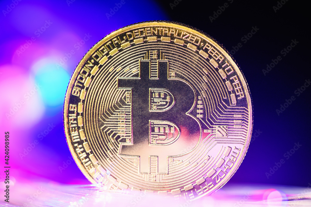 Gold Bitcoin coin with blue and pink backlight with a glint. Crypto currency. Bitcoin mining concept