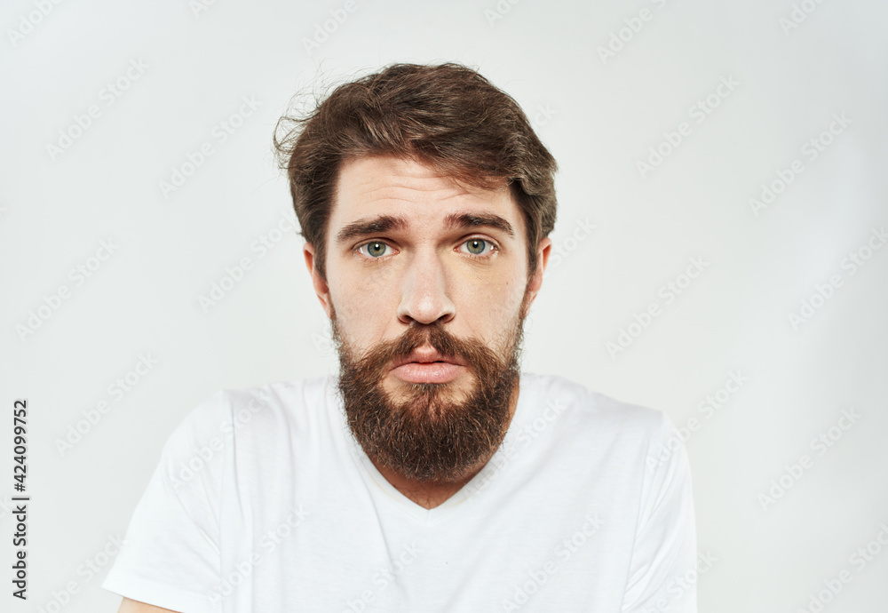 Bearded man in white T-shirt puzzled look sad face cropped look