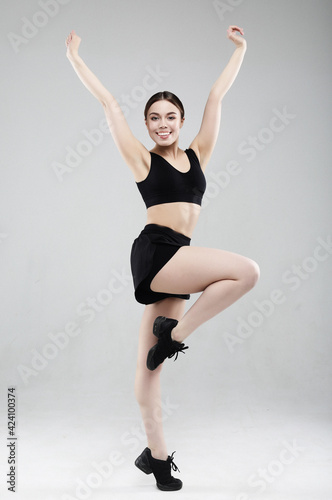 Full length portrait of a young fitness woman in sportswear posing and jumping isolated over gray background © Raisa Kanareva