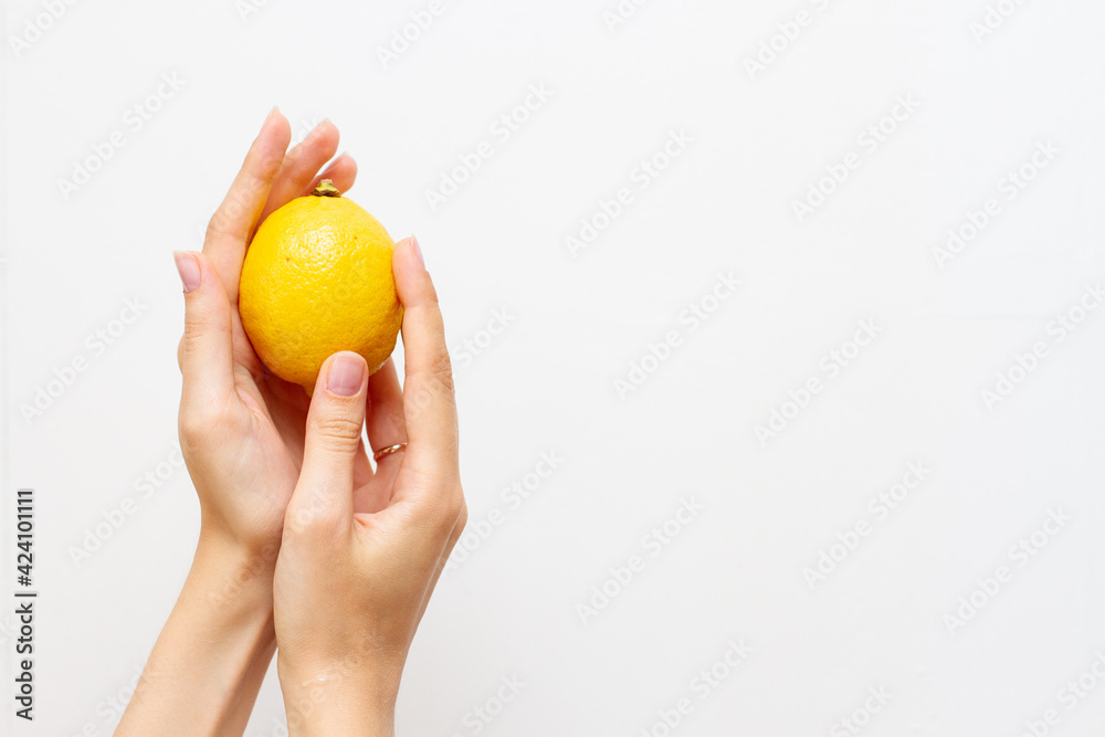 Fresh lemon in a woman hand on a white background Fresh lemon in a woman hand on a white background