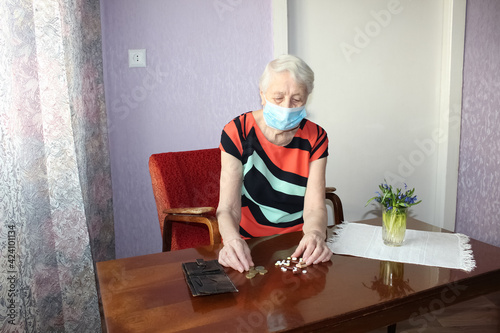 Happy positive smiling senior woman takes off protective medical mask from face outdoors