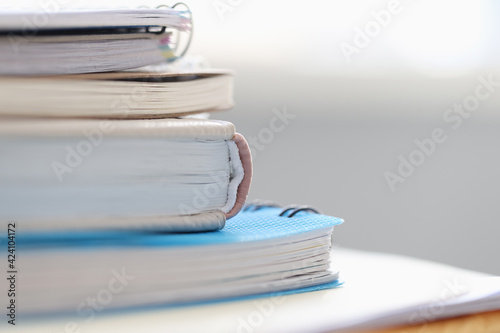 Stack of books and notebooks lying on table closeup