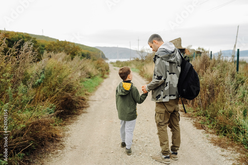 dad and son in military khaki clothes go off-road with a backpack for traveling. family hiking trips. local tourism. selective focus