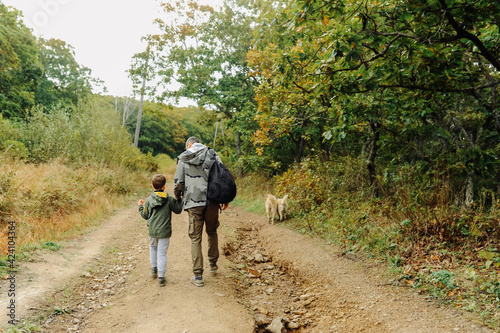 dad and son in military khaki clothes go off-road with a backpack for traveling. family hiking trips. local tourism. travel with pets. selective focus © Aleksandra
