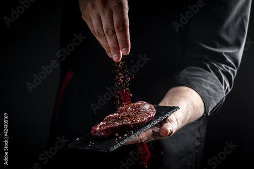 Slika na platnu Chef hands cooking meat steak and adding seasoning in a freeze motion