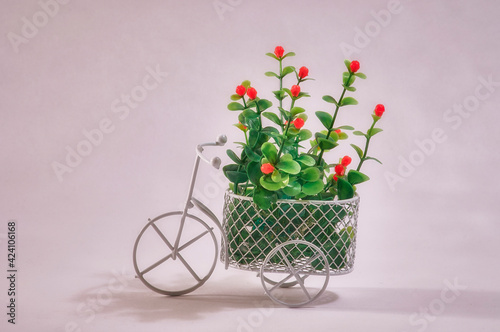 Flowers in a basket of a toy bike on a gray background.