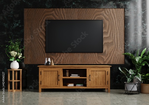 TV on the wooden wall in the living room Decorated with wooden cabinets and plants on tiled floors. There is a dark marble wall as a background.3d rendering.