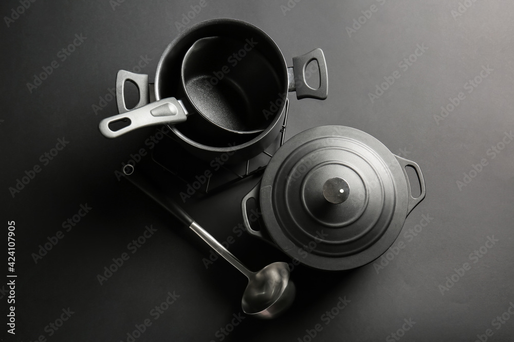Cooking pots and ladle on dark background Cooking pots and ladle on dark background