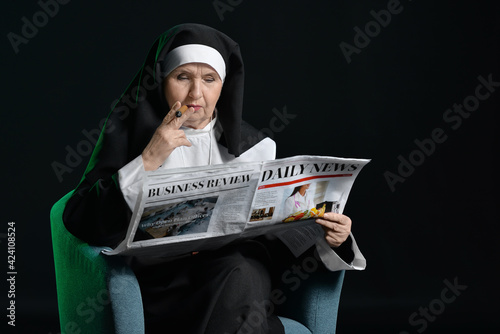 Senior nun with newspaper a...
