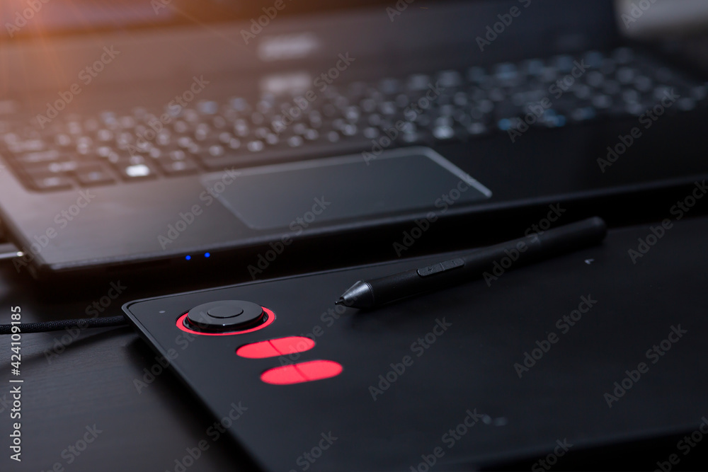 Close-up of a laptop with a graphics tablet on a black table. Designer workplace, freelance worker Close-up of a laptop with a graphics tablet on a black table. Designer workplace, freelance worker