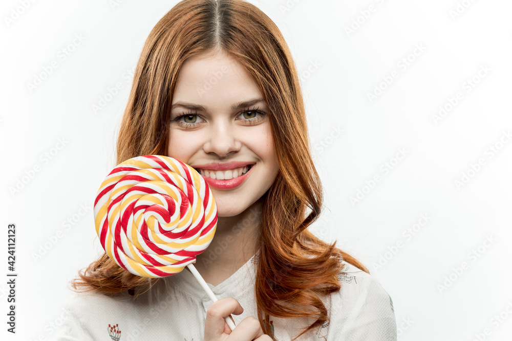 pretty red-haired woman with a round lollipop in her hands emotions joy sweets candy