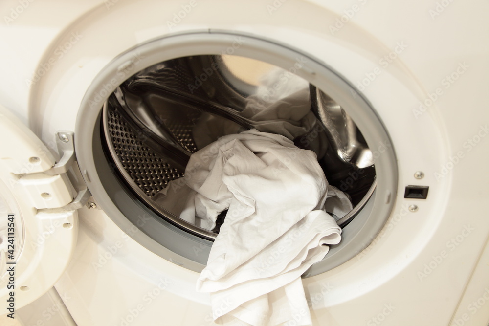 White clothing in front loaded washing machine can with stainless steel rotor and opened door closeup