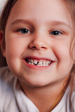 close-up portrait of a positive, proud five-year-old girl with a toothless smile from a newly fallen first baby tooth.