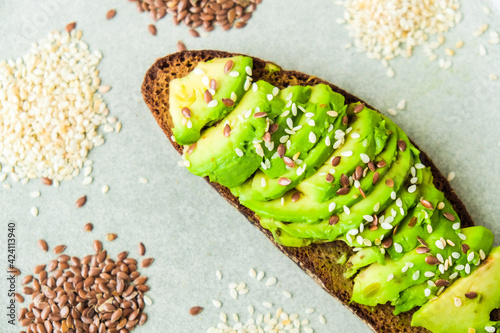 Healthy avocado toast on concrete background. Wholegrain bread, sesame flax seeds. Vegan keto diet. Healthy eating. Trendy guacamole sandwich photo