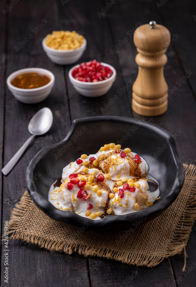 woman garnishing or serving Dahi Bhalla or Dahi Vada with tamarind sauce, pomegranate seeds, and boondi woman garnishing or serving Dahi Bhalla or Dahi Vada with tamarind sauce, pomegranate seeds, and boondi