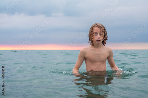 Young blonde teenage boy enjoys the sea at the beach.