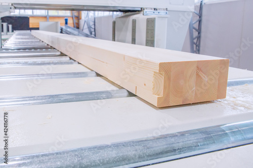 Glued laminated timber lies on a woodworking machine. Selective focus on laminated veneer lumber.