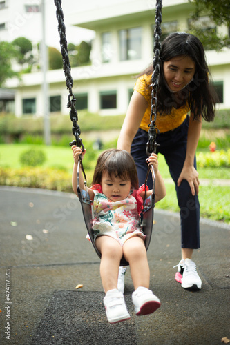 cute little girl playing swing with her mommy © Ivan