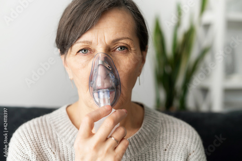 Photo Headshot of sick senior lady using oxygen mask at home, a mature woman has labor
