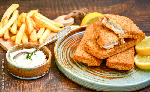  Fish and chips .Close up of   crispy breaded  deep fried fish fingers with breadcrumbs served with remoulade sauce and  lemon