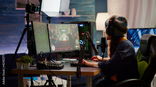 Woman streamer checking sound using professional mixer for streaming video games in gaming home studio. Pro gamer playing first person shooter video games talking with team mates on open chat photo