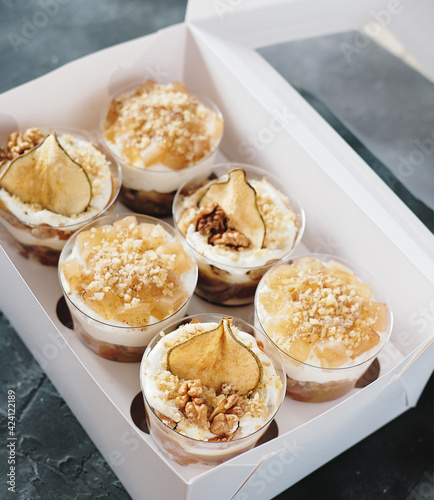 Set of Pear trifle, chocolate biscuit, layered dessert with caramel, pear and gentle cream cheese in a box. Selective focus photo