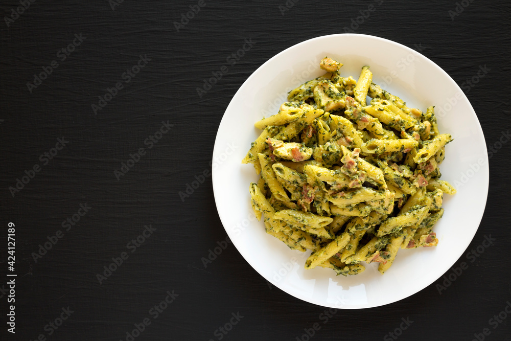 Homemade One-Pot Chicken Spinach Bacon Alfredo Pasta on a plate on a black background, top view. Space for text.