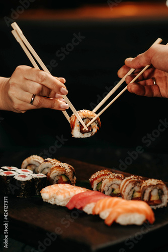 Man and woman pick up sushi with chopsticks at the same time