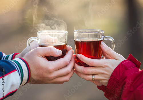 Loving young couple holding hands and hot tea outdoors 