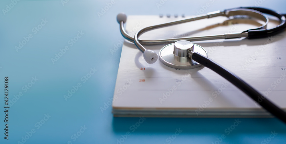 Stethoscope with date on calendar page on wooden table medical concept Stethoscope with date on calendar page on wooden table medical concept