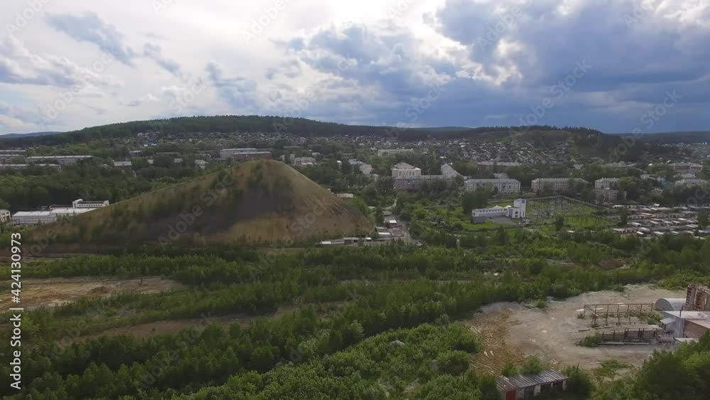 Aerial view of small Provincial industrial city. On the outskirts of the city there are low houses, garages, power station and Industrial dumps. Summer evening, in the sky doe clouds and blue clouds. Aerial view of small Provincial industrial city. On the outskirts of the city there are low houses, garages, power station and Industrial dumps. Summer evening, in the sky doe clouds and blue clouds.