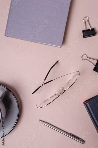 Top vew of workplate.Glasses, notebook, cup, binder clips on the desk photo