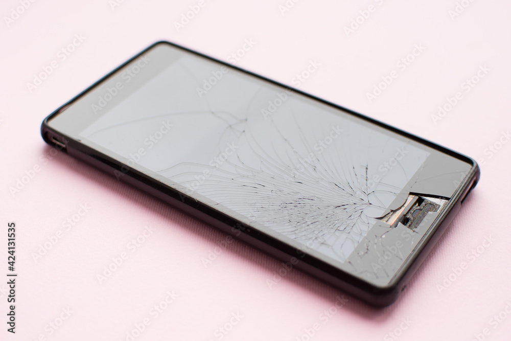 Broken mobile phone on pink background Broken mobile phone on pink background
