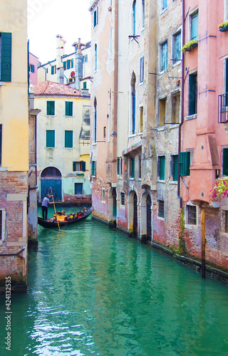 Beautiful narrow canal with gondolas and small boats and historical buildings in Venice, Italy