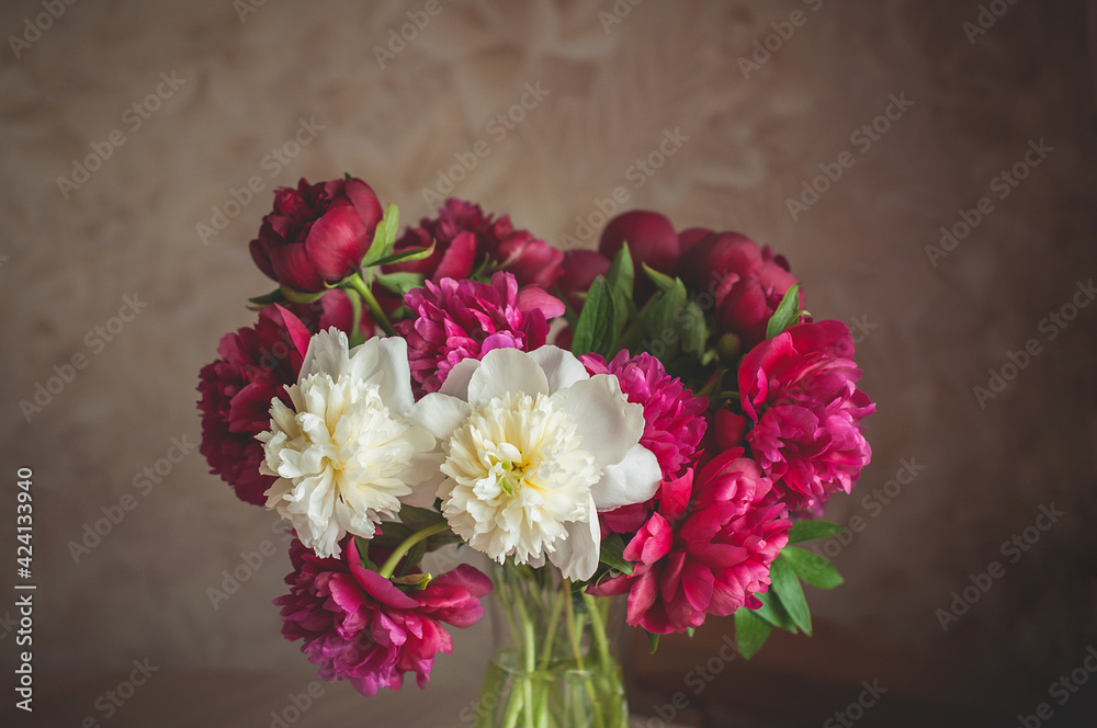 A colorful bouquet of peony flowers in a glass vase