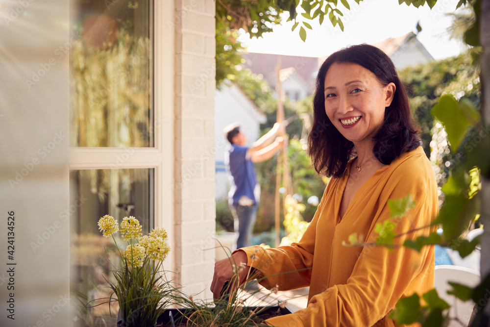 Portrait Of Mature Asian Woman Planting Plants Into Wooden Garden Planter At Home Portrait Of Mature Asian Woman Planting Plants Into Wooden Garden Planter At Home