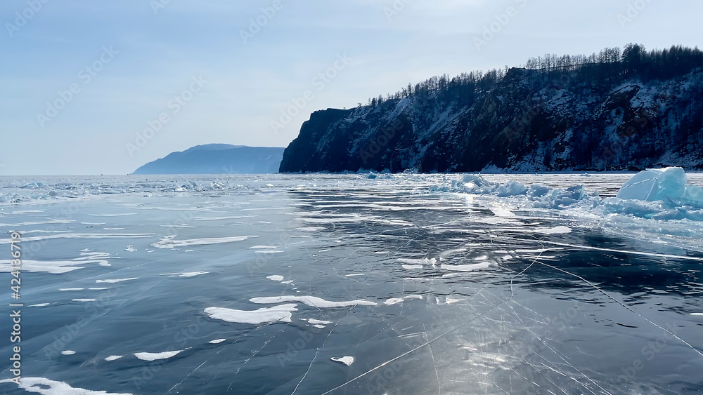 Panorama of frozen Lake Baikal. A beautiful winter landscape with blue transparent ice